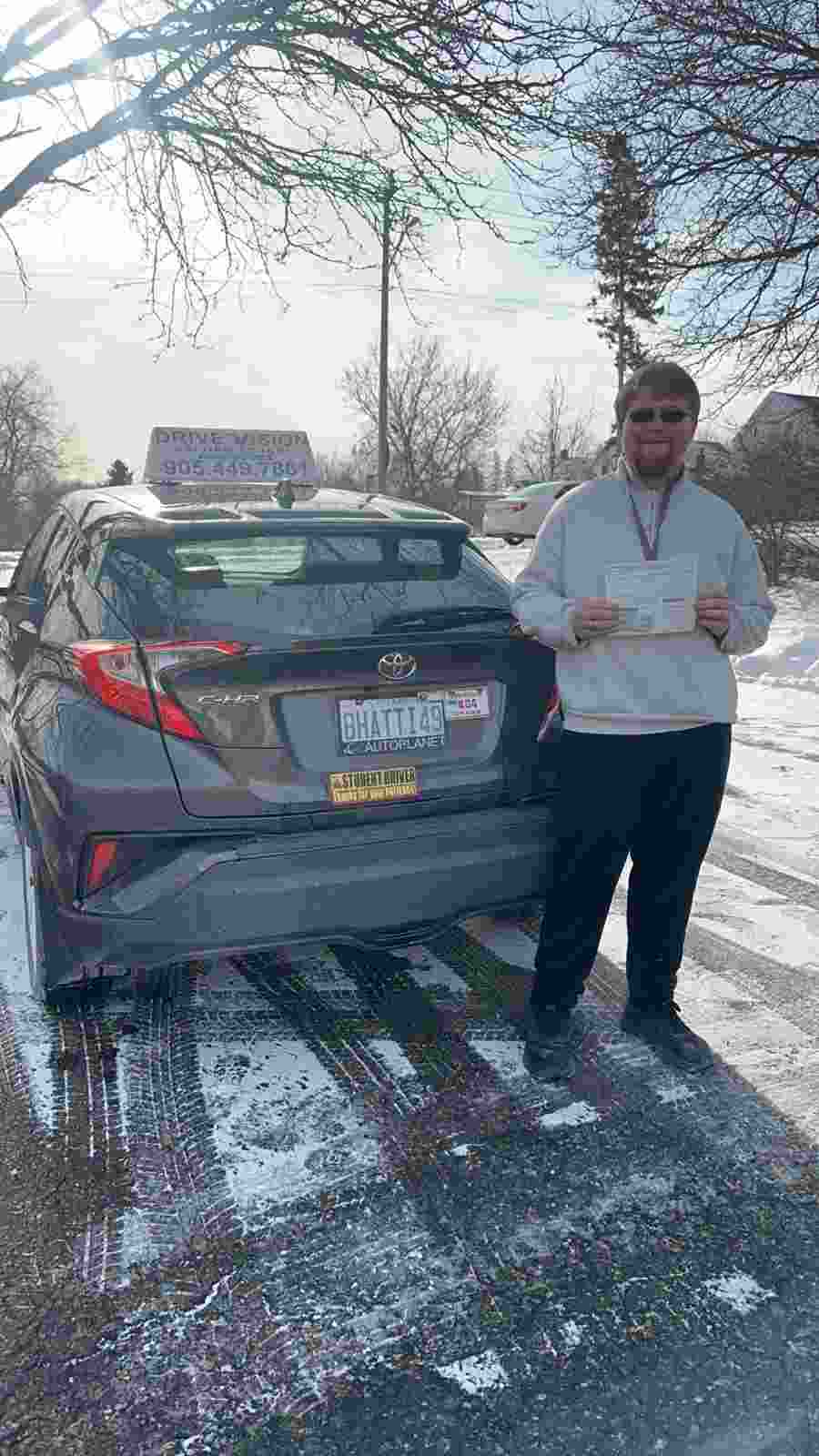 a man holding a driving licence issued by drive vision driving school